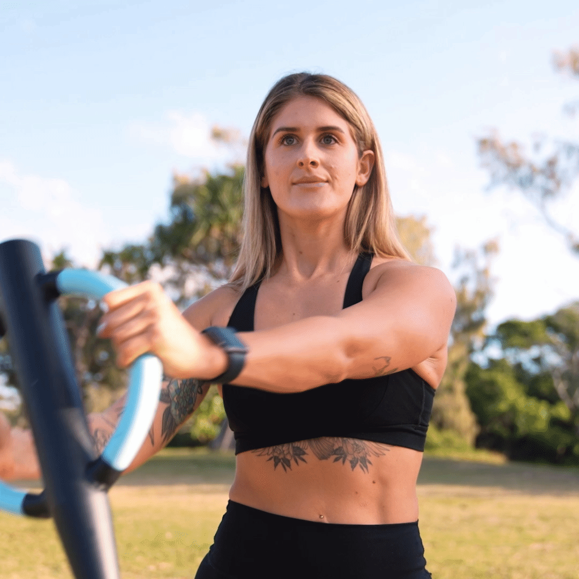 GIF Image of a women kneeling holding the butterfly barbell vertically by the dual-handles and rotating the bar side-to-side to workout her abdominal muscles.